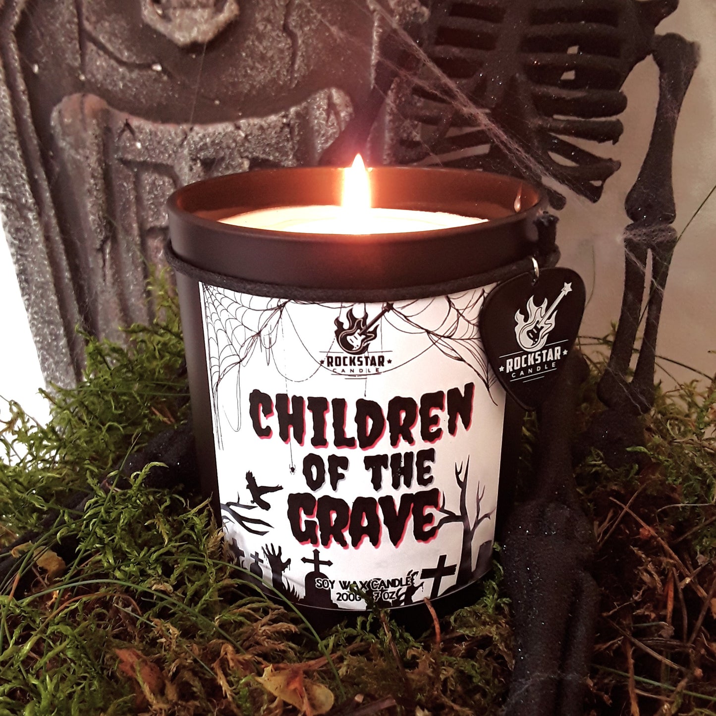 Kerze Children of the Grave vor Halloween-Dekoration mit Skelett, Moos und Grabstein