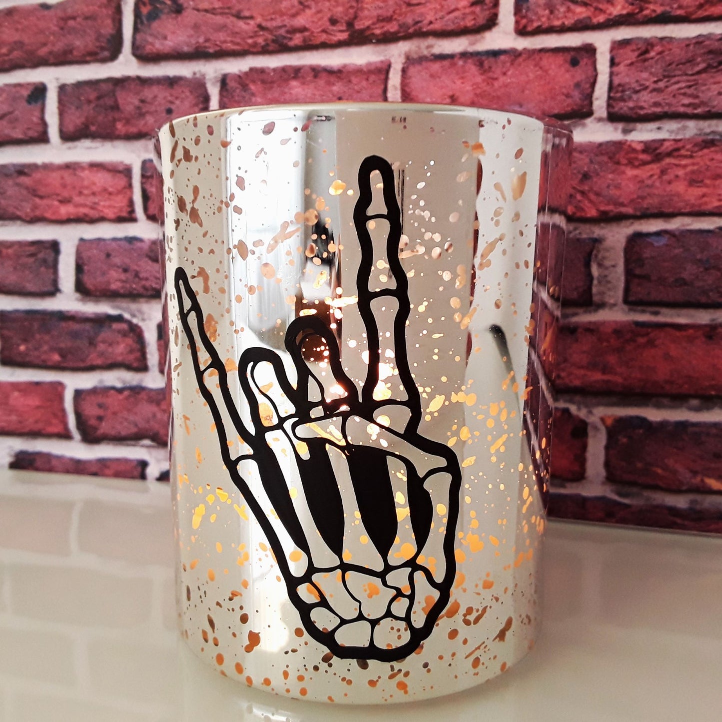 Kerze silber Skeletthand brennend vor Backsteinwand Detailfoto