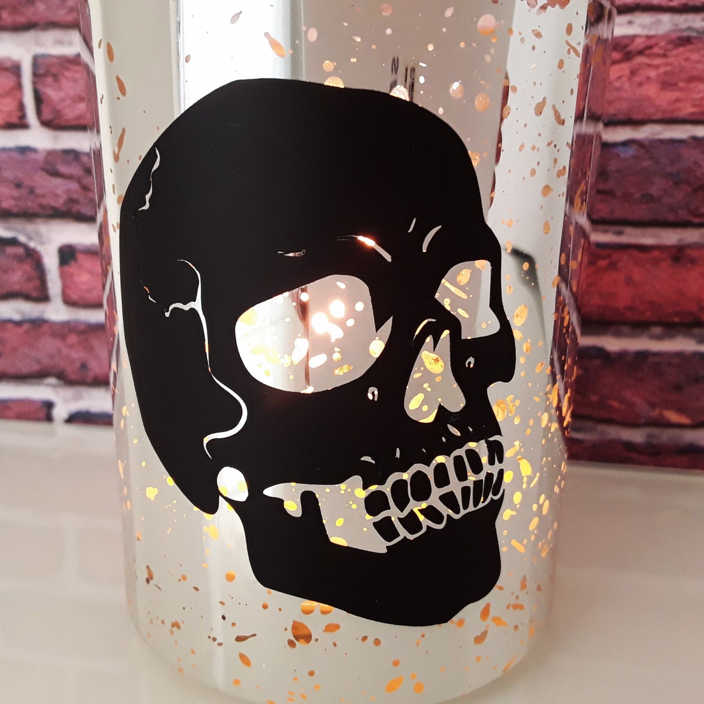 Kerze silber Schädel brennend Detailfoto vor Backsteinwand