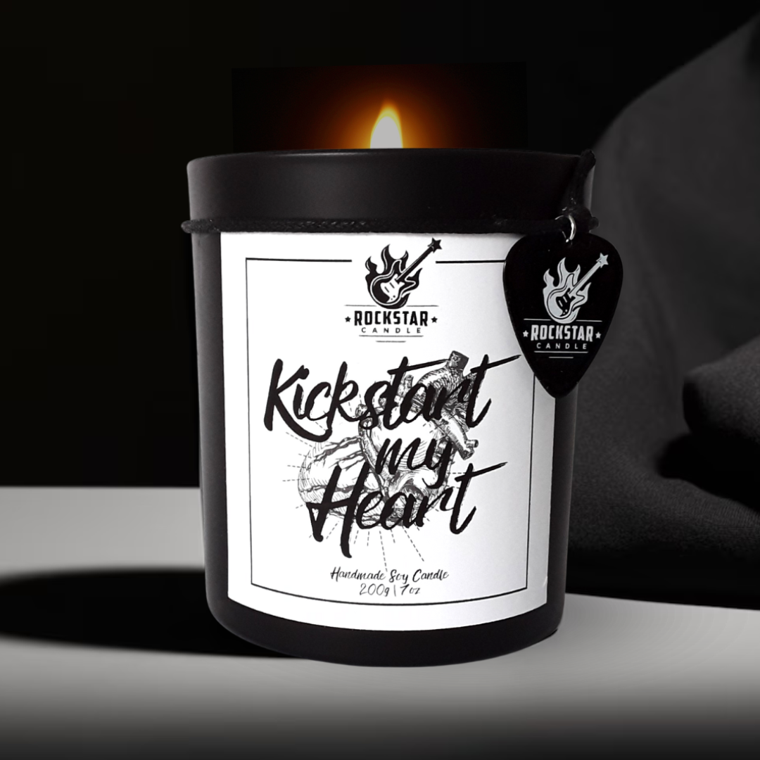 Kerze Kickstart my heart brennend vor schwarzem Hintergrund