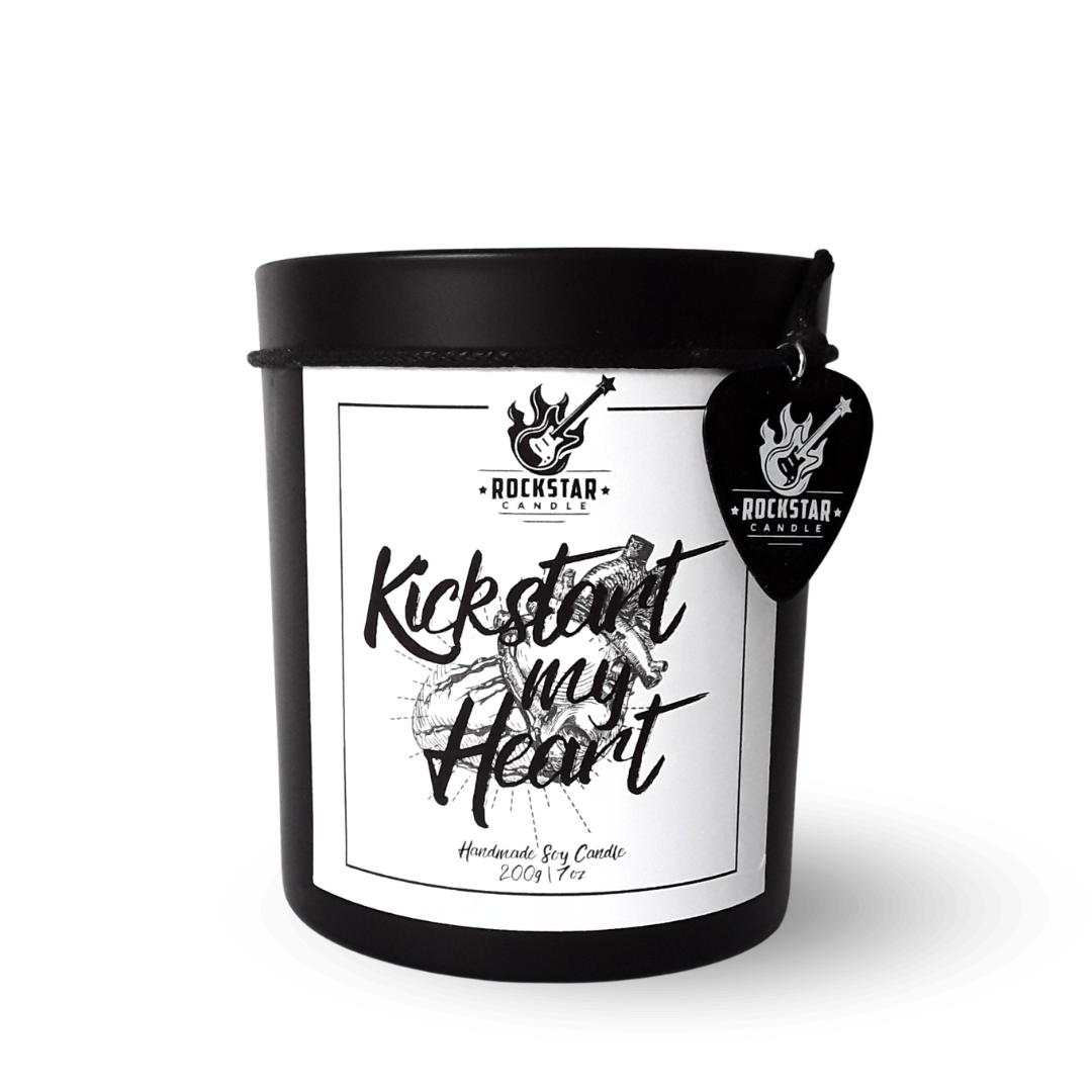 Schwarzes Kerzenglas mit Aufschrift Kickstart my heart und Gitarrenplektrum mit Rockstar Candle Logo als Dekoration.