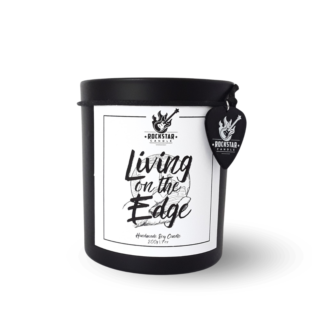 Schwarzes Kerzenglas mit Aufschrift Living on the edge und Gitarrenplektrum mit Rockstar Candle Logo als Dekoration.