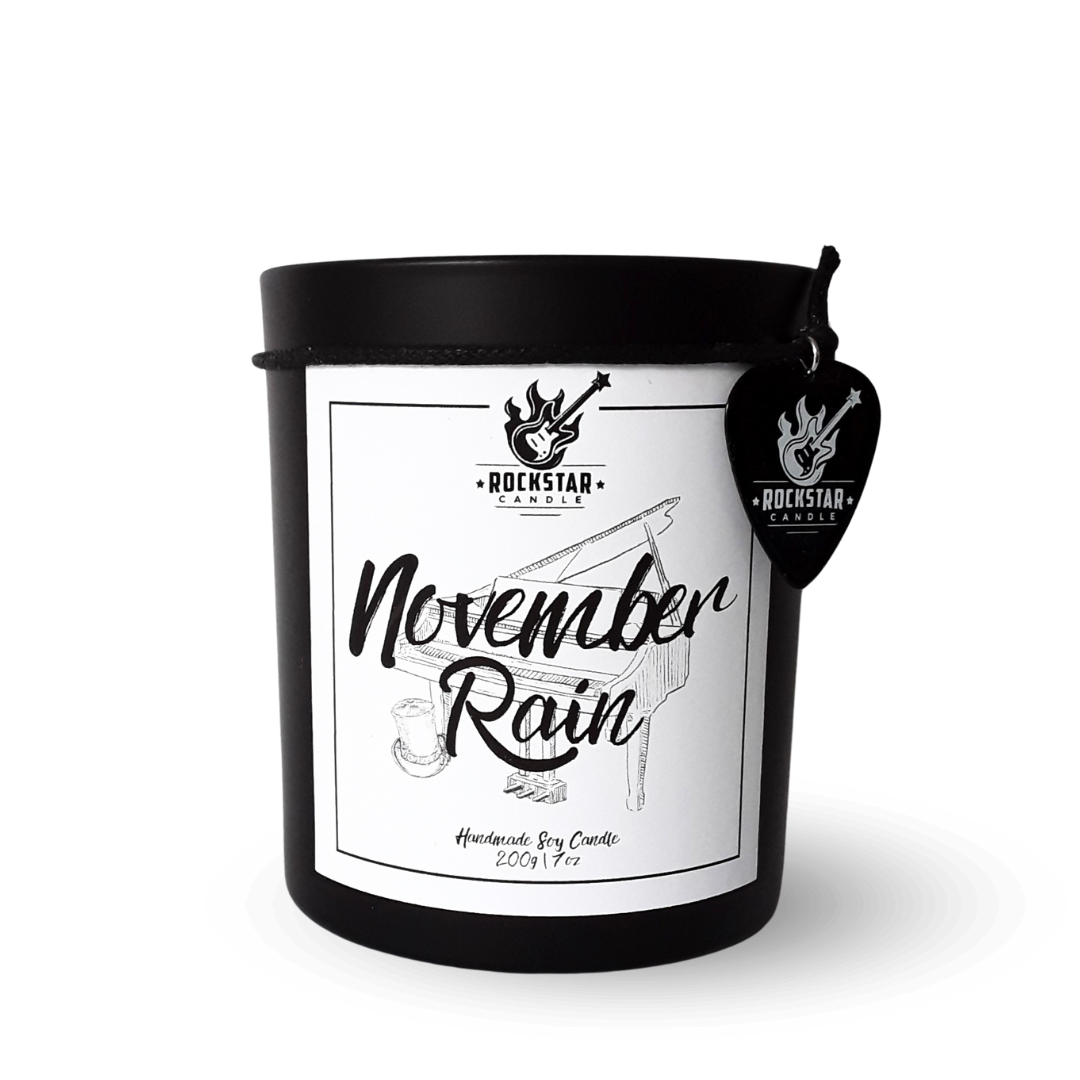 Schwarzes Kerzenglas mit Aufschrift November Rain und Gitarrenplektrum mit Rockstar Candle Logo als Dekoration.