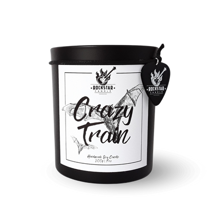 Schwarzes Kerzenglas mit Aufschrift Crazy Train und Gitarrenplektrum mit Rockstar Candle Logo als Dekoration.