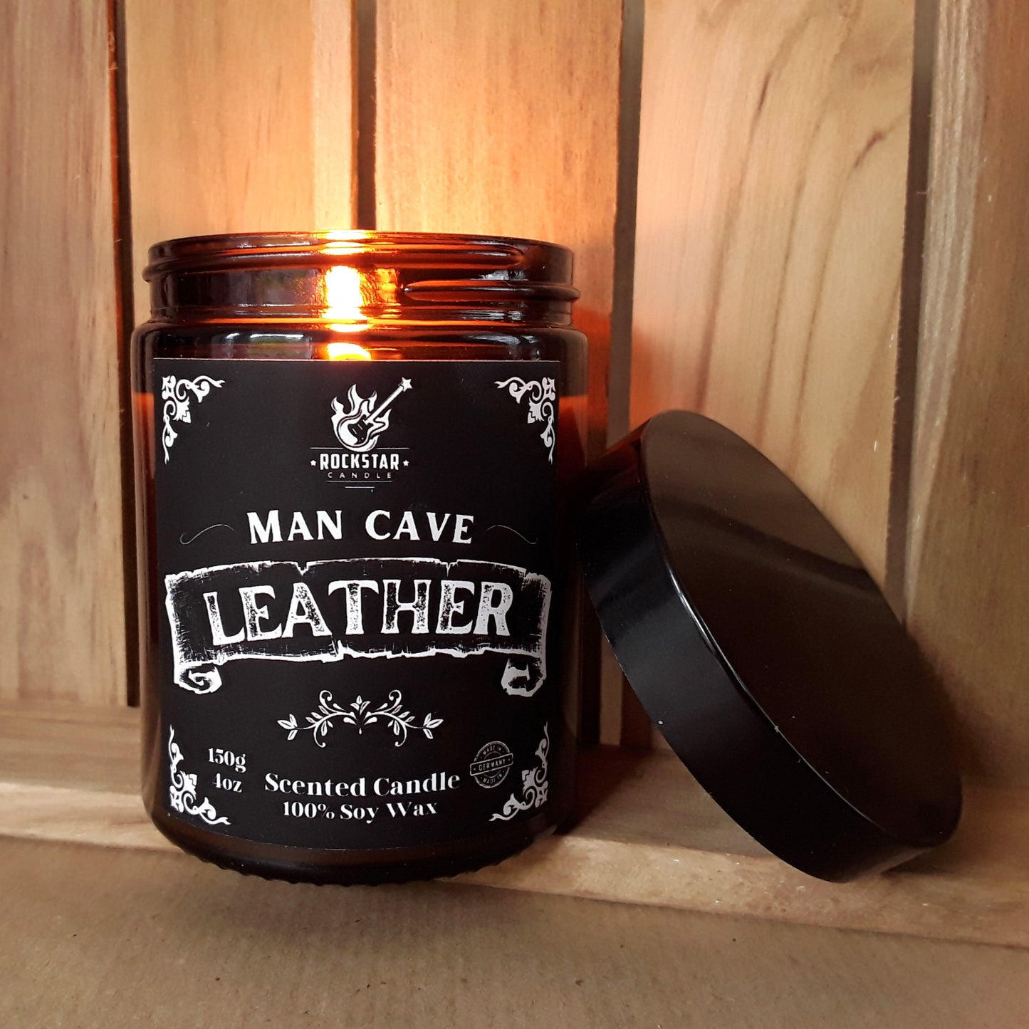 Brennende Kerze im braunen Glas, schwarzes Etikett mit weißer Beschriftung Leather 