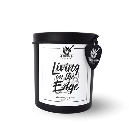 Schwarzes Kerzenglas mit Aufschrift Living on the edge und Gitarrenplektrum mit Rockstar Candle Logo als Dekoration.